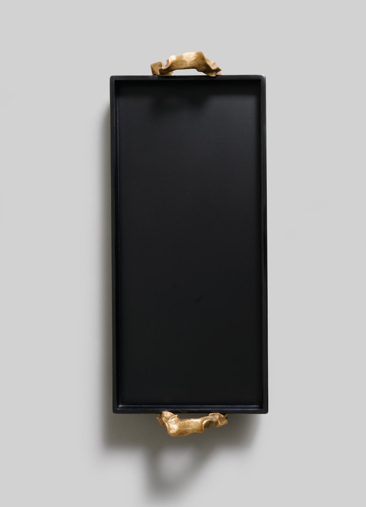 The VIYA Saffron Black Vanity Tray features two gold animal handles, blending ancient Indian-inspired elegance with modern style, displayed on a light gray background.