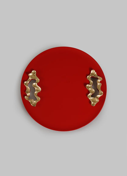 The VIYA Saffron Red Tray Small is a round, bright red serving tray with two wavy gold handles, shown on a plain light gray background.