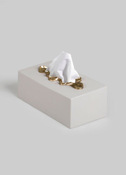 The VIYA Saffron Tissue Box Large is a rectangular white box with a tissue partially pulled out, framed by a wavy gold border reminiscent of contemporary bronzed decor, shown against a plain light gray background.