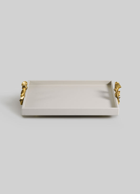 The VIYA Saffron Ecru Towel Tray is a rectangular white tray with raised edges and elegant gold handles on each side, inspired by traditional vessels for presenting saffron, shown against a plain light gray background.
