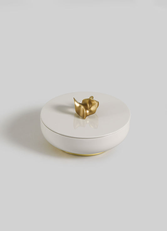 The VIYA Saffron Ecru Trinket Box Large is a round, white ceramic container with a fitted lid and a unique small gold abstract handle, displayed against a plain light gray background.