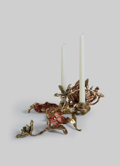 A decorative candle holder made of metal with a twisted, organic design resembling coral or natural forms, finished in a bronze or antique gold tone, holding two white tapered candles.