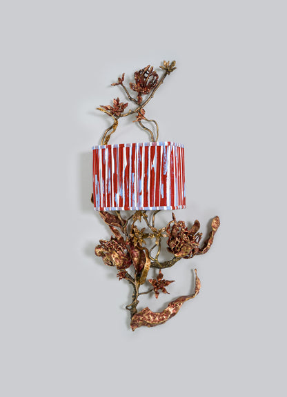 The VIYA Spring In Kashmir Wall Sconce A features bronze, branch-inspired metalwork with red flower accents, a patina finish, and a cylindrical lampshade with red and white stripes—perfect for Kashmir home decor.
