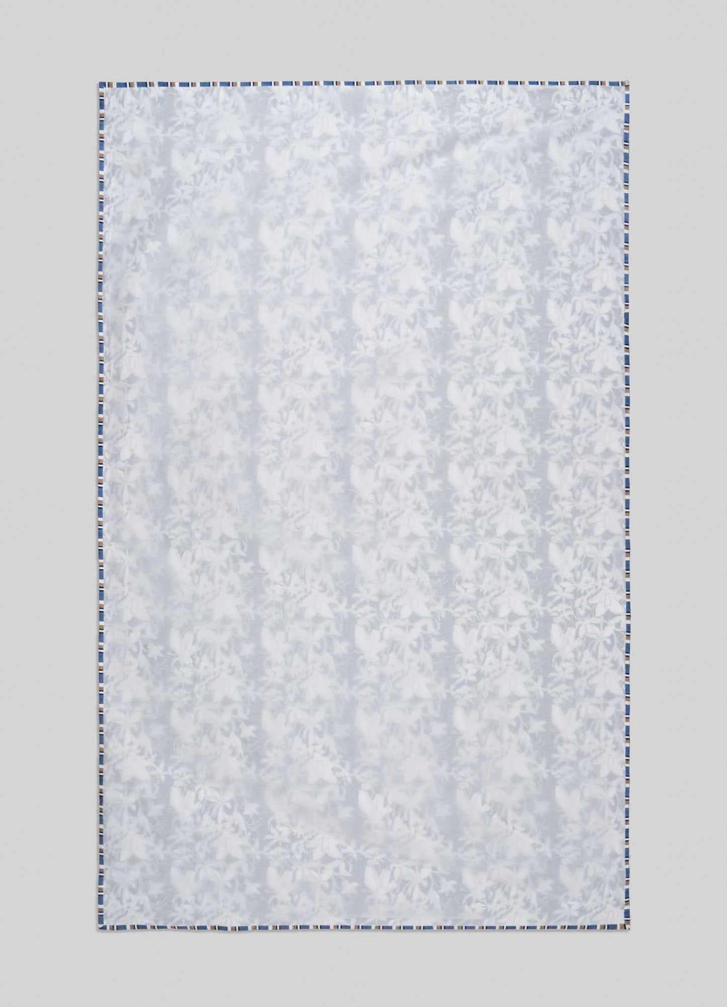 The Viya Spring Bouquet Blue Single Dohar features a subtle floral pattern inspired by Indian gardens, finished with a blue-and-white border, and is displayed flat against a light gray background.