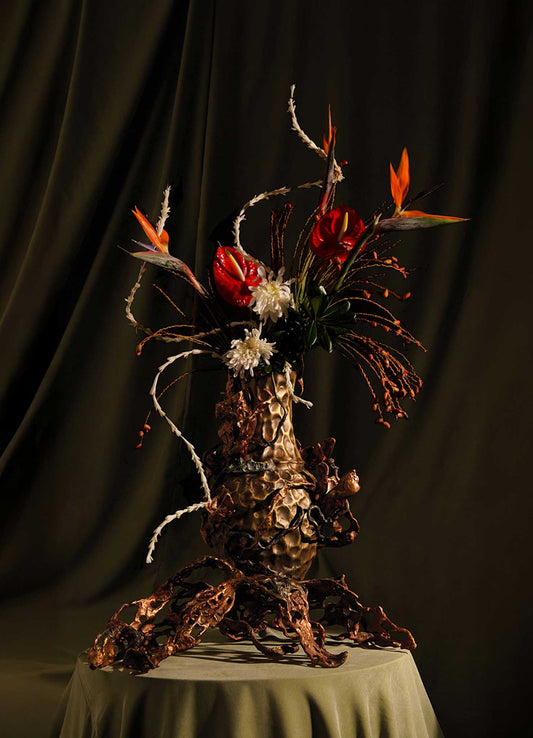 The VIYA Spring In Kashmir Vase Large features a dramatic floral arrangement in a pinecone-textured vase with sculptural brown metal roots, blooming tulips, and exotic flowers, perfect for adding Kashmiri elegance to any room.