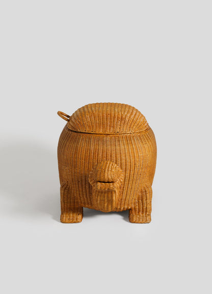 The VIYA Tortoise Laundry Basket is crafted with cane weaving techniques, featuring a rounded body, four short legs, and a small lid on top, all set against a plain gray background.