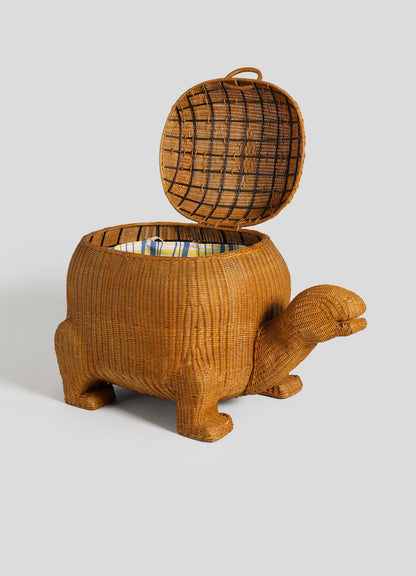 The VIYA Tortoise Laundry Basket is a finely woven cane basket shaped like a tortoise, with a hinged lid for storage, four legs, and detailed head and tail features.