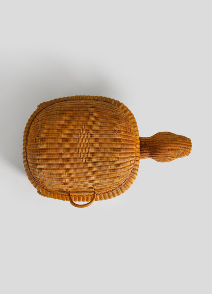The VIYA Tortoise Laundry Basket is an oval, cane-woven basket with a handle and a natural textured finish, shown from above on a plain light grey background.