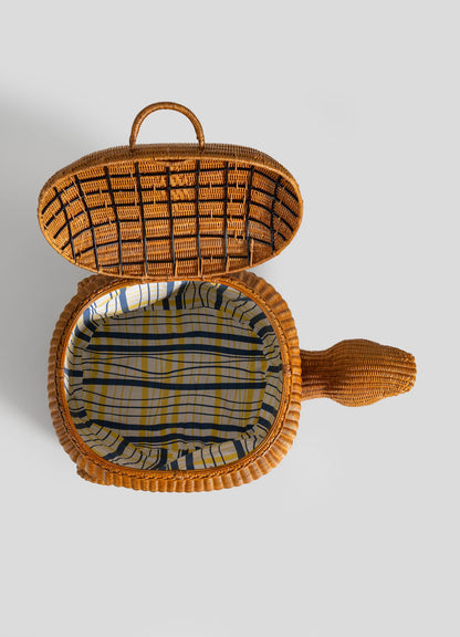The VIYA Tortoise Laundry Basket features a woven wicker turtle design, shown from above with its lid open to reveal a blue, yellow, and white plaid fabric lining—crafted using traditional cane weaving techniques.