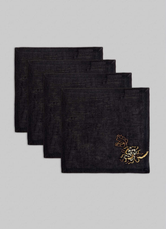 The Viya Tree Full of Parrots Hand Embroidered Black & Gold Cocktail Napkins (set of 4) feature intricate designs symbolizing blessings and good fortune, shown staggered atop a light gray background.